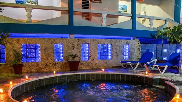 A spa area with a hot tub, blue chairs, and potted plants. - Hotel Tronco Inc (Boca Chica)
