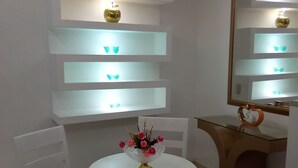 A room with a round white table, a chair, a mirror, and shelves with decorative items. - Hotel Tronco Inc (Boca Chica)