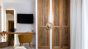 A bedroom with a bed, a bedside table, a TV, and a wardrobe with a woven door. - Ktima Lino (Naxos)