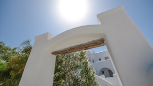 A white building with a wooden archway and a clear blue sky. - Ktima Lino (Naxos)
