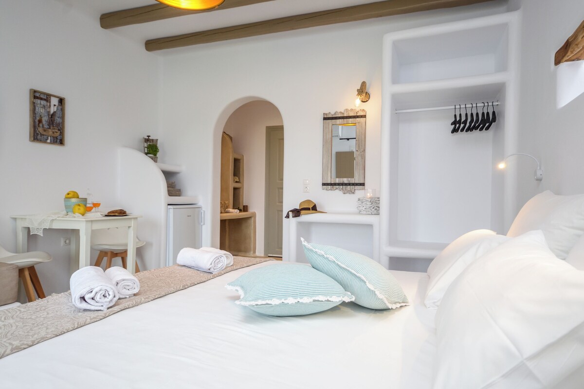 Una habitación de hotel con cama, escritorio, espejo y armario.