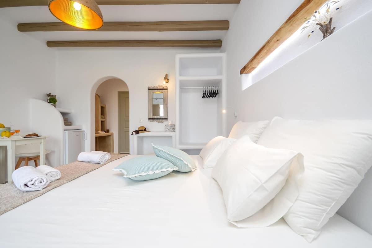 Ein Schlafzimmer mit Bett, Schreibtisch, Stuhl, Spiegel und einer Hängeleuchte.