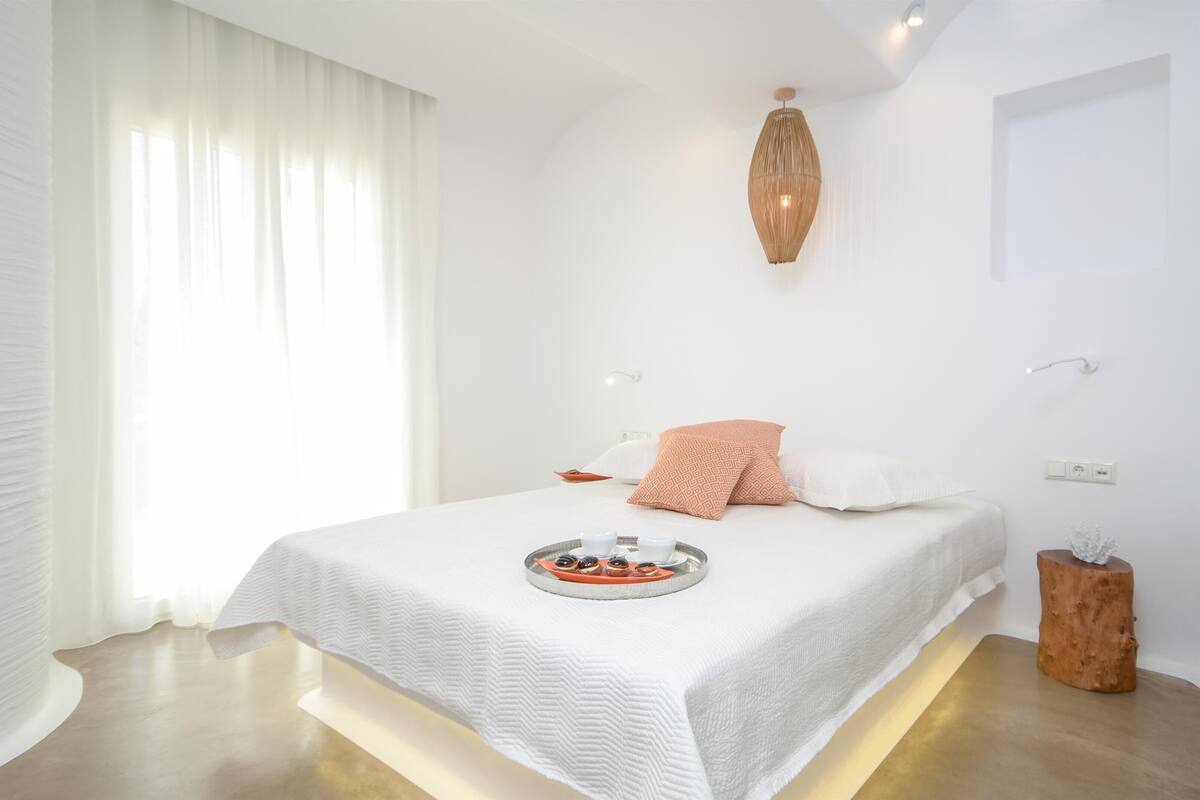 A modern bedroom with a bed, bedside table, and a tray with snacks.