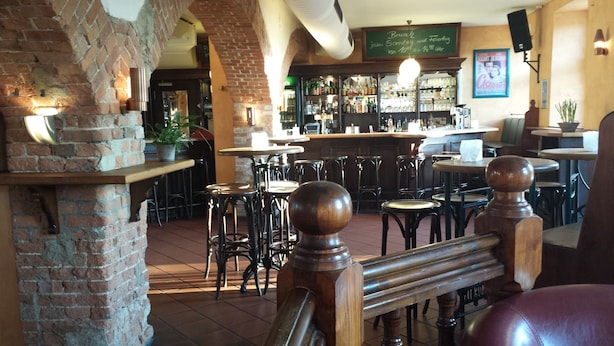 Una zona de bar con taburetes, una pared de ladrillo y una baranda de madera.