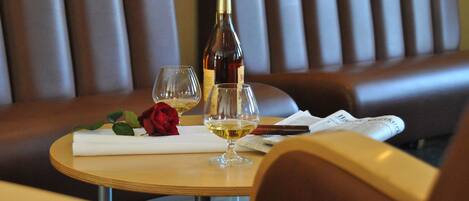 A table with a bottle of wine, two glasses, a rose, and a menu.