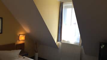 A hotel room with a bed, a bedside lamp, a radiator, and a television.