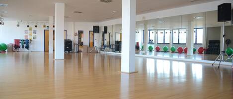 A spacious room with a polished wooden floor, white walls, and large mirrors.