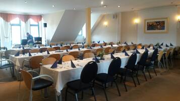 Ein Konferenzraum mit mehreren Tischen und Stühlen, die in Reihen angeordnet sind.