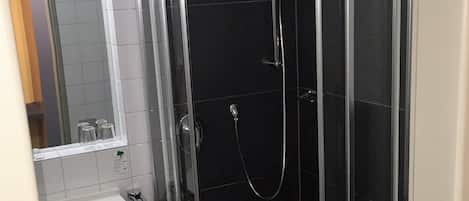 A modern bathroom with a glass-enclosed shower, a white sink, and a toilet.