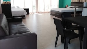 A modern hotel room with a bed, a sofa, a desk, and a dining table.