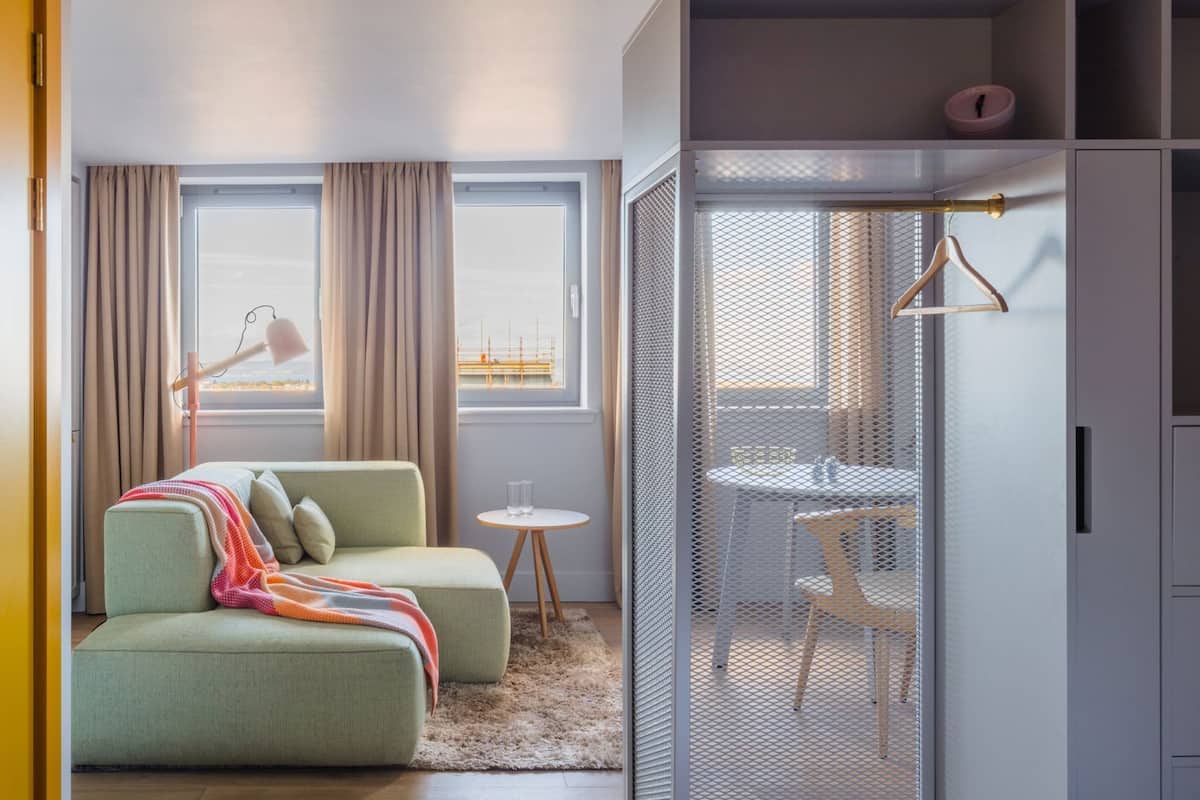 A modern room with a sofa, a small table, a hanging light, and a view of a construction site.