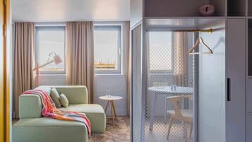 A modern room with a sofa, a small table, a hanging light, and a view of the outside.