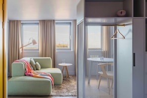 A modern room with a sofa, a small table, a hanging light, and a view through a mesh partition.