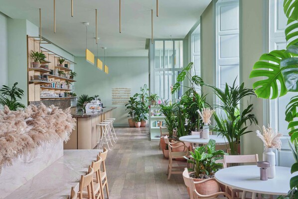 A modern interior with a bar area, seating, and abundant indoor plants.