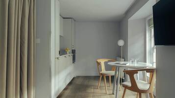 A modern kitchen with white cabinets, a dining table with two chairs, and a large window.