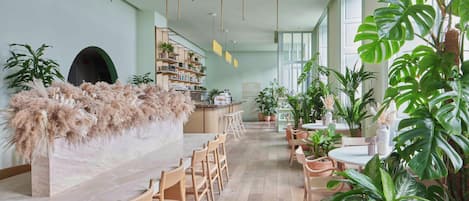 A modern interior with a marble bar, wooden chairs, and potted plants.