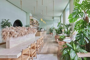 Un interior moderno con una barra de mármol, sillas de madera y plantas en macetas.