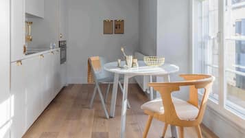 A kitchen with white cabinets, a round table, two chairs, and a window.