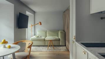 A modern kitchen with a marble countertop, a dining area with a round table and chairs, and a green sofa in the background.