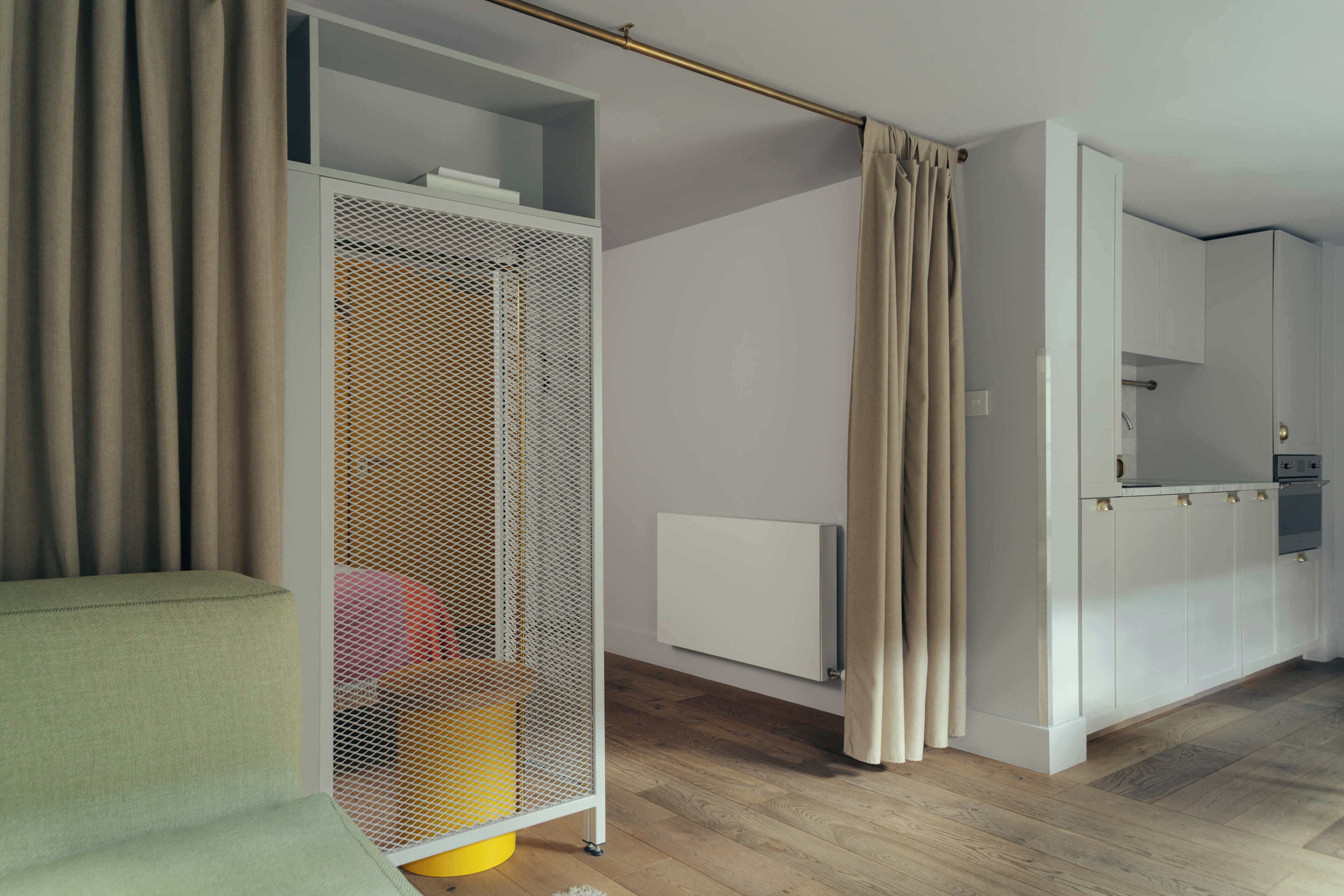 A modern interior with a sofa, a white cabinet, a radiator, and a curtain.