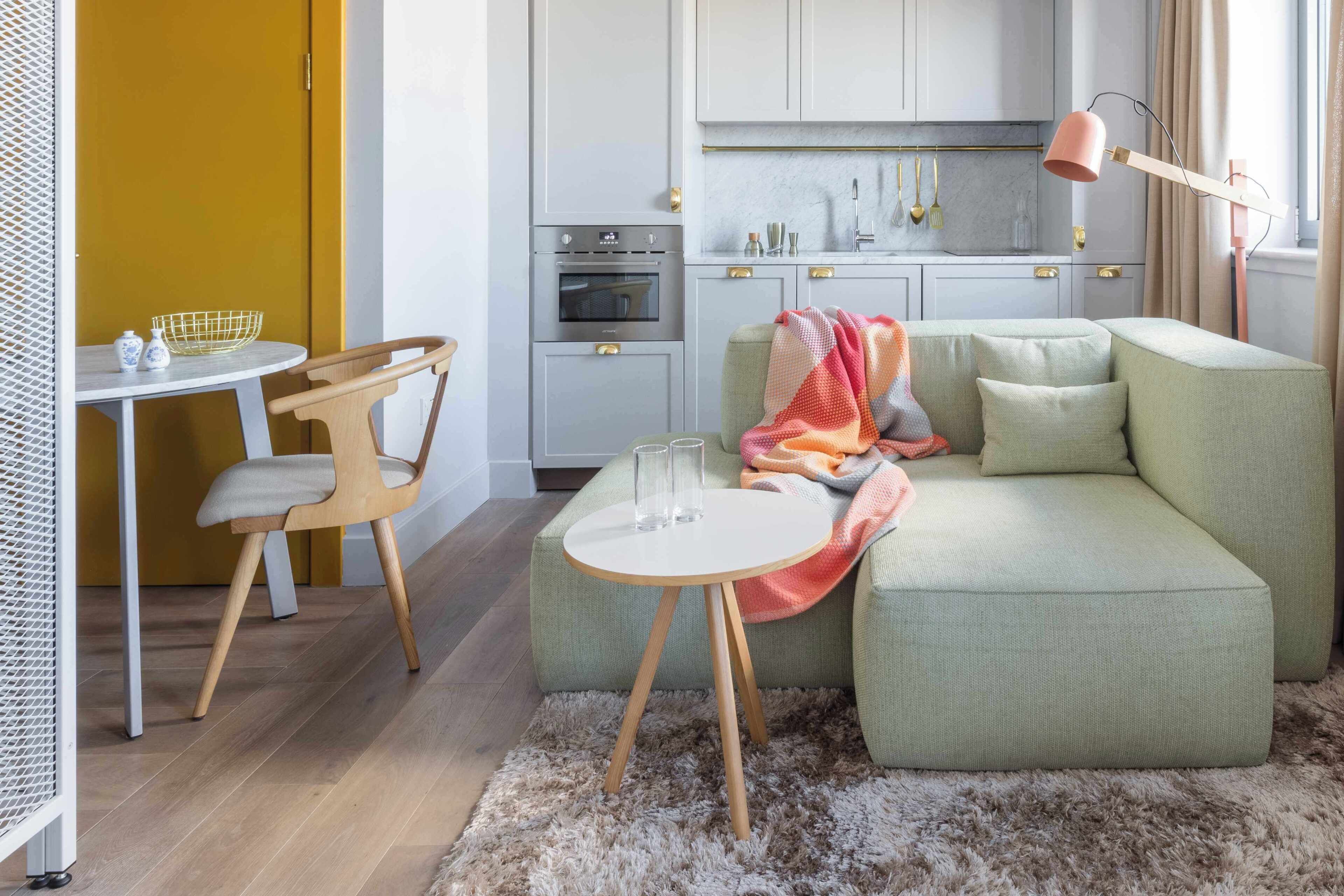 A modern kitchen with a dining area, a sofa, and a small table with chairs.