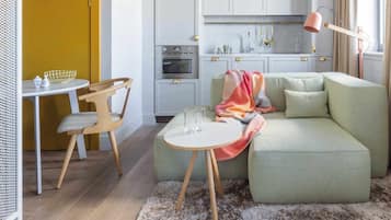 A modern kitchen with a dining area, a sofa, and a small table with chairs.