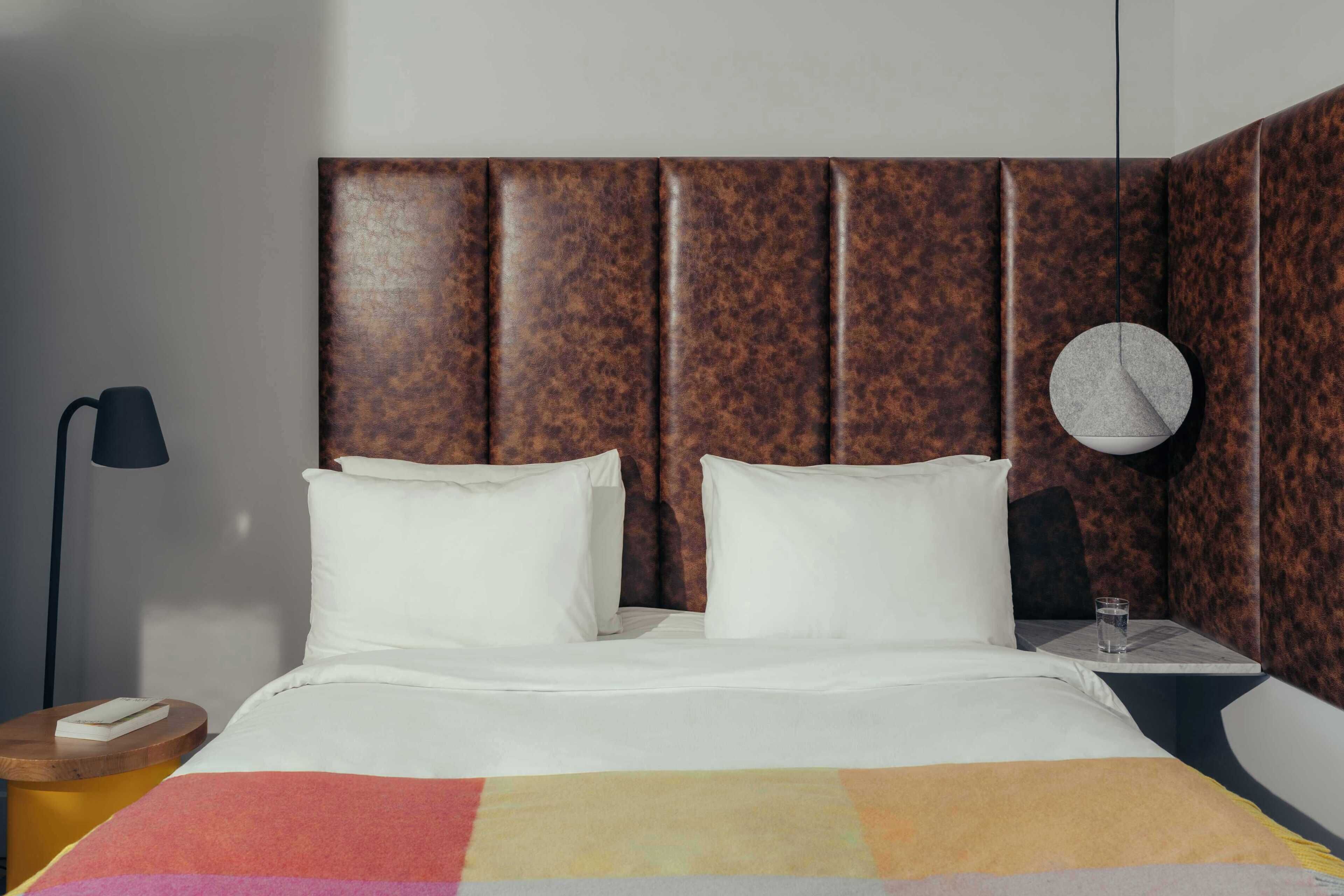 Habitación de hotel con cama, un reloj redondo, una mesita de noche y una lámpara.
