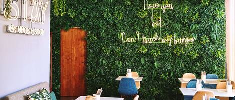 Een restaurant interieur met een groene wand, een houten deur en tafels met stoelen.