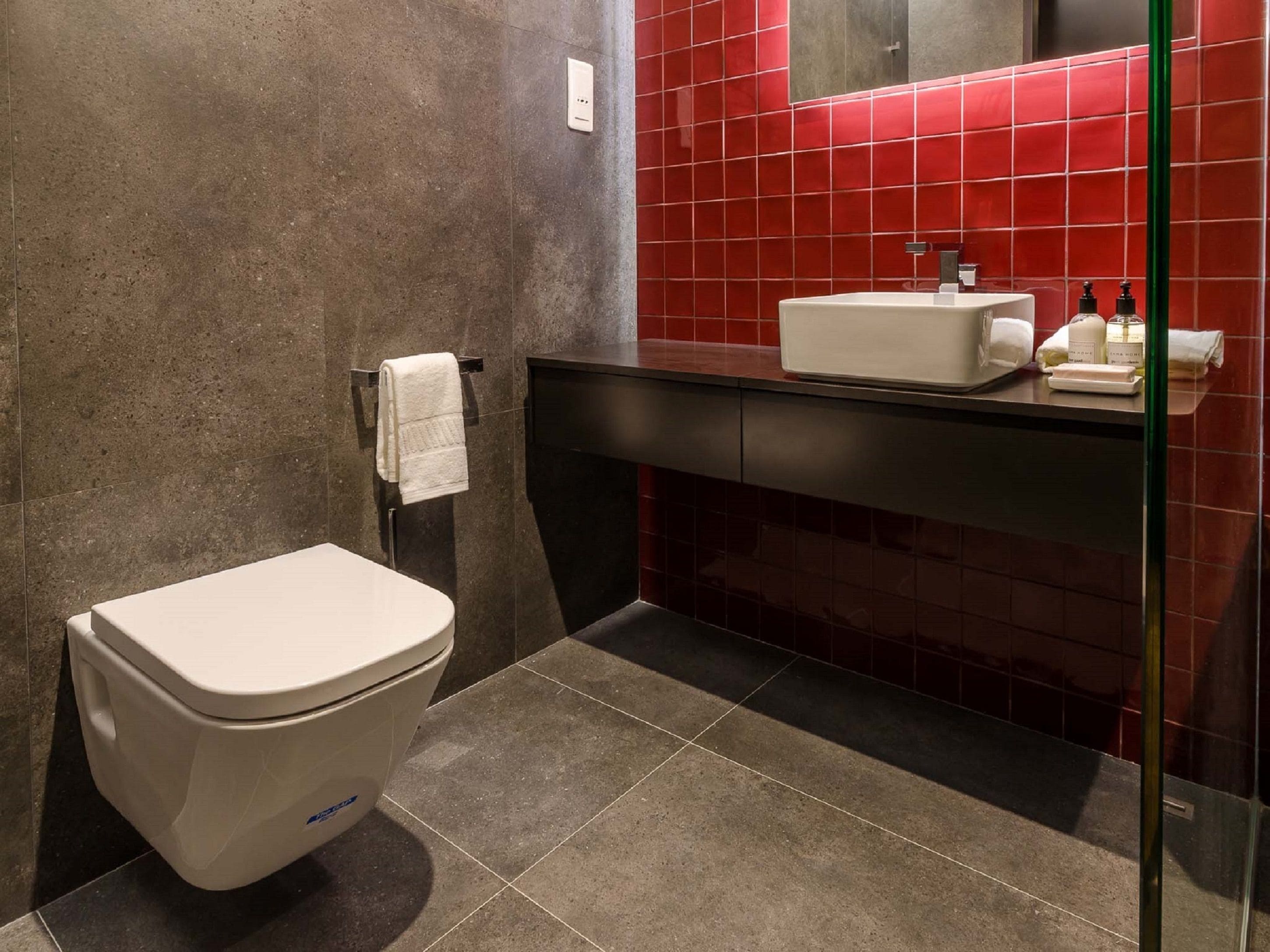 Een badkamer met toilet, wastafel en spiegel.