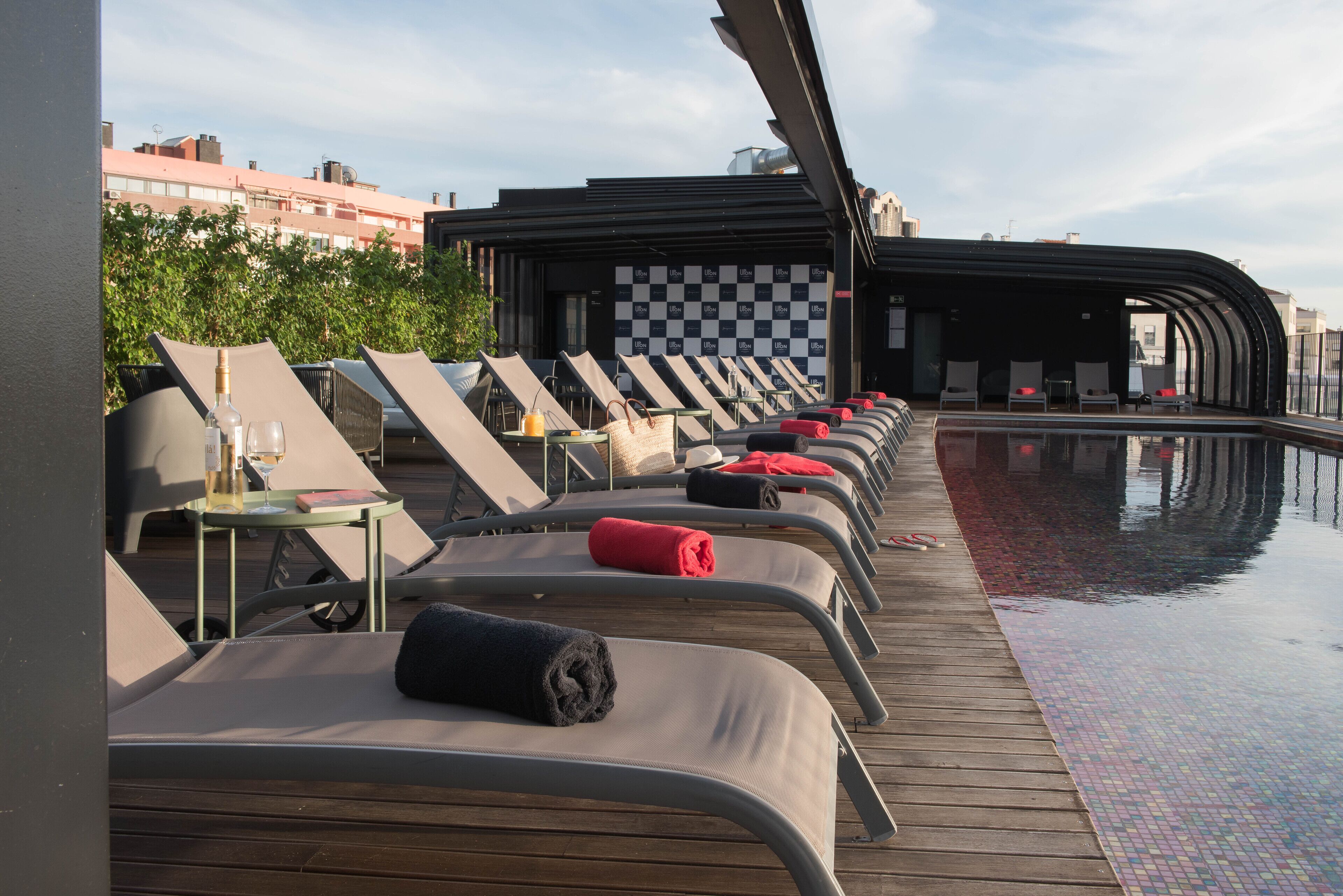 A poolside area with lounge chairs and a checkered wall in the background.