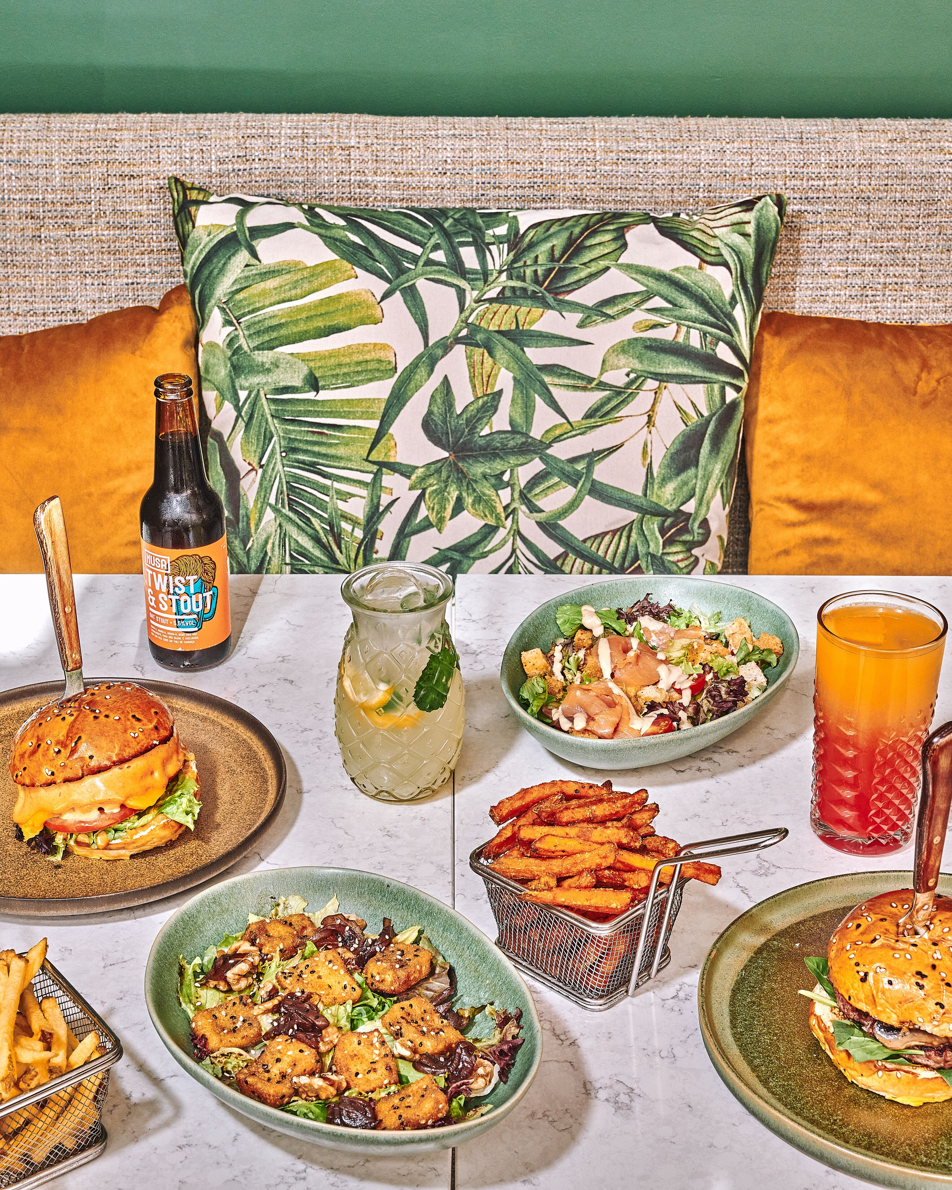 A dining table with various dishes, a bottle of beer, and a glass of orange juice.