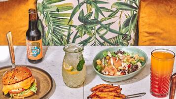 A dining table with various dishes, a bottle of beer, and a glass of orange juice.