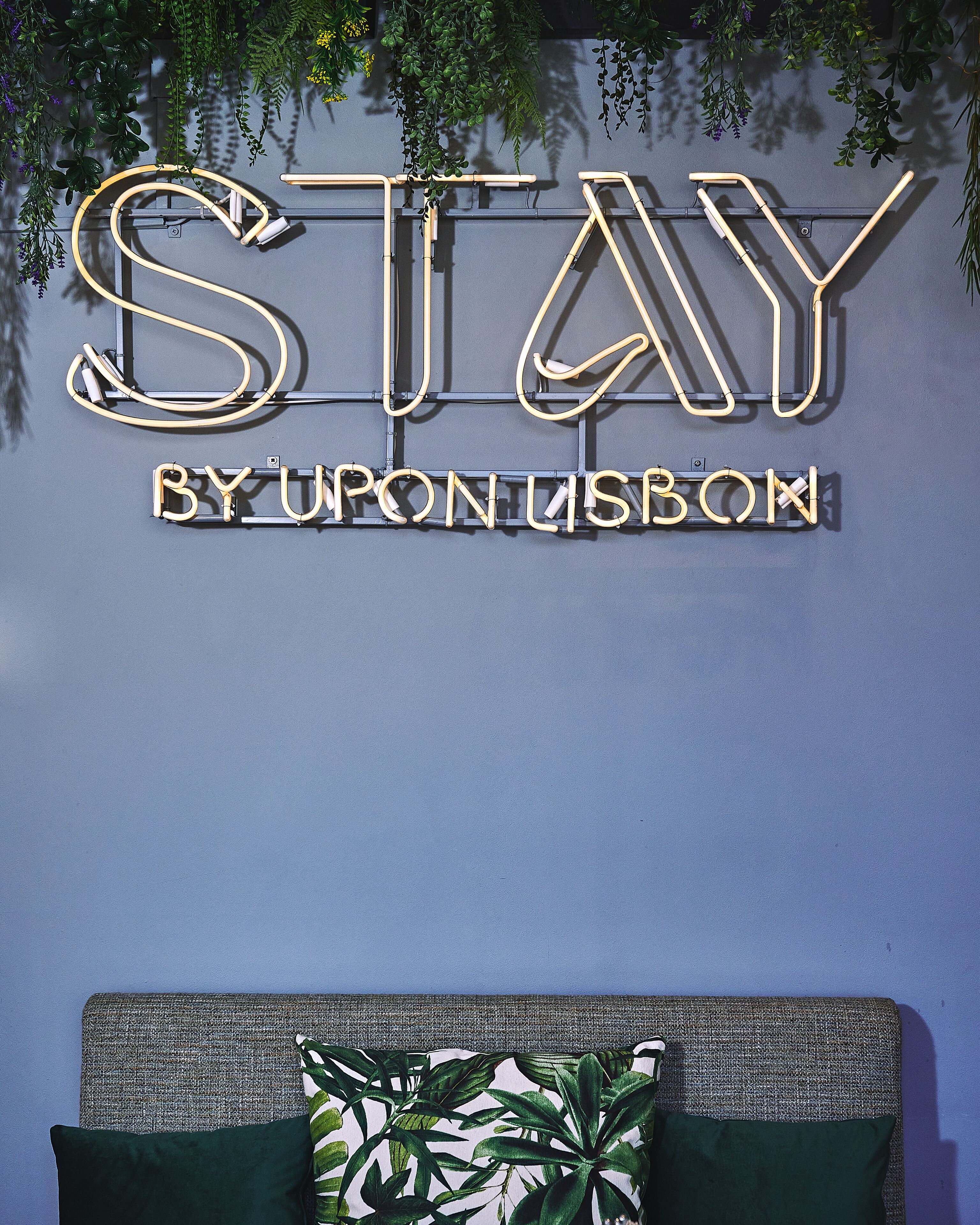 Una pared con un letrero de neón que dice "STAY BY URON LISBON".