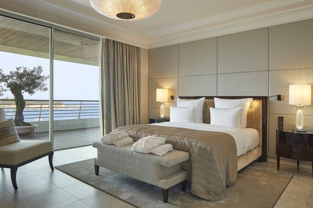 Une chambre d’hôtel dotée d’un grand lit, d’un coin salon, d’un balcon avec vue et d’un lustre.