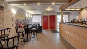 A modern hotel lobby with a reception desk, seating area, and a mural on the wall. - ConfortT Hotel Thouars (Thouars)
