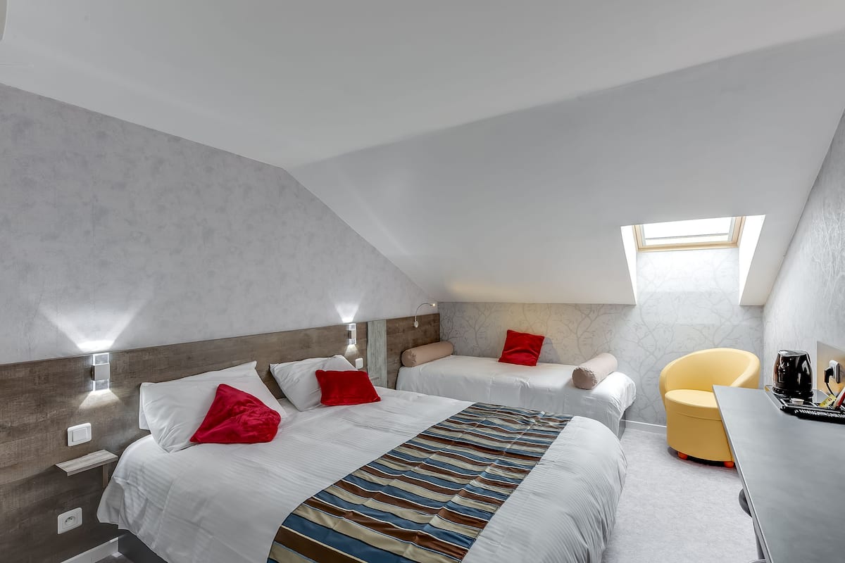 Ein modernes Hotelzimmer mit zwei Betten, einem Schreibtisch und einem Stuhl.