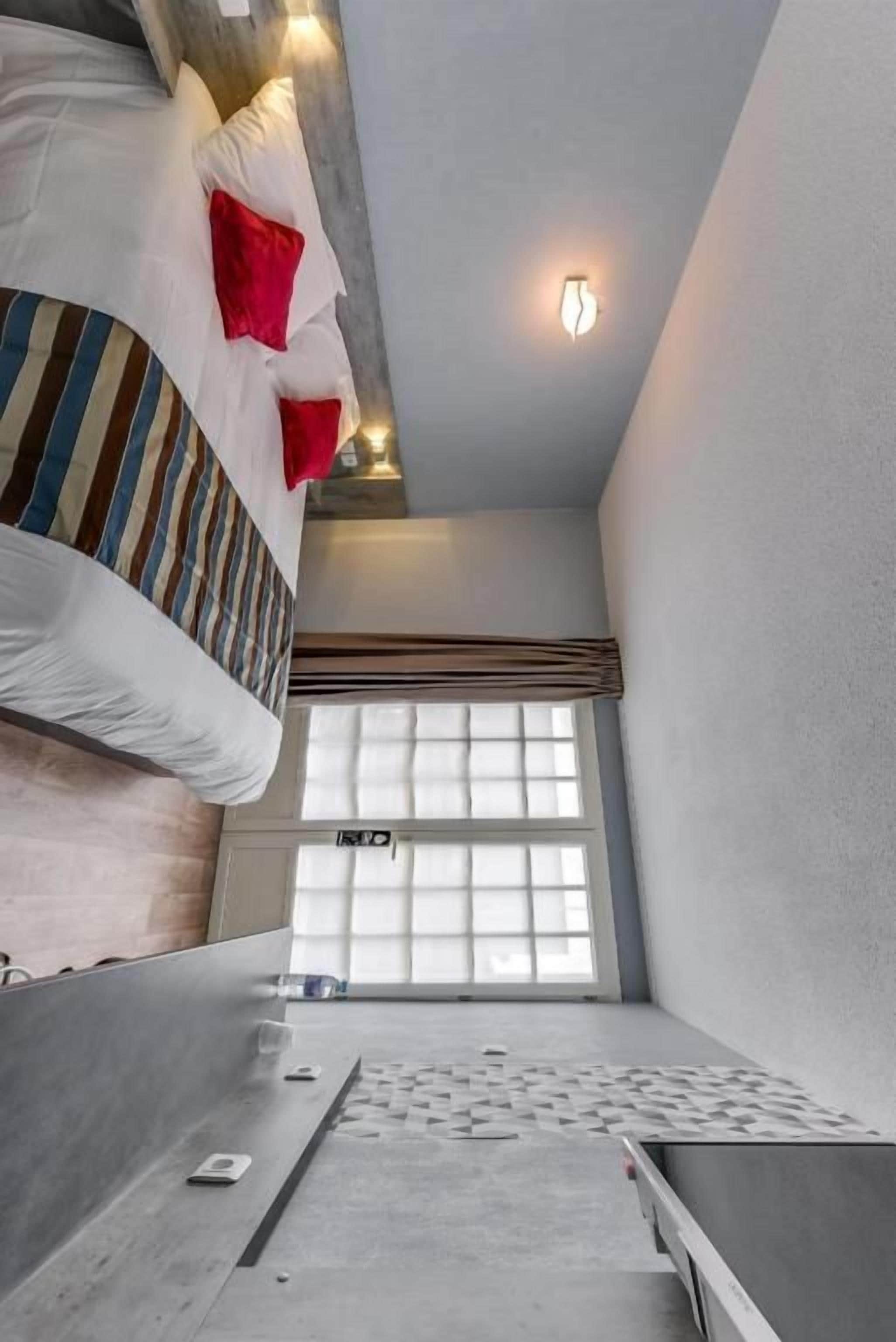 A compact room with a bunk bed, a small table, and a window with blinds.