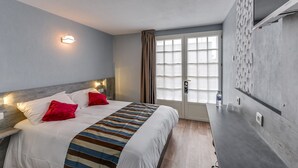 A modern hotel room with a large bed, a nightstand, a wall-mounted TV, and a window with curtains. - ConfortT Hotel Thouars (Thouars)