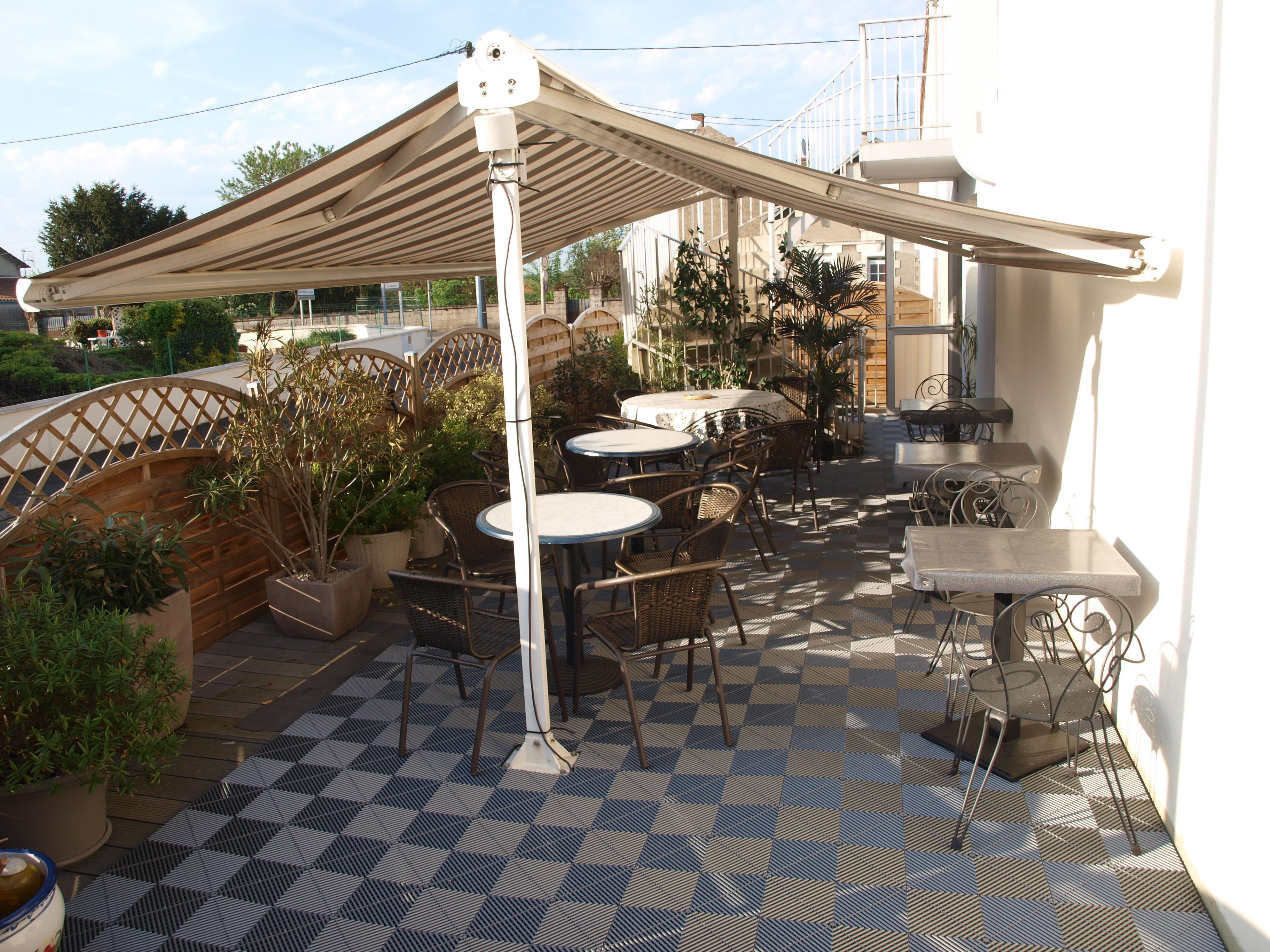 An outdoor patio with tables and chairs, a pergola, and potted plants.