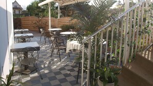 An outdoor patio area with tables and chairs, a covered seating area, and a staircase. - ConfortT Hotel Thouars (Thouars)
