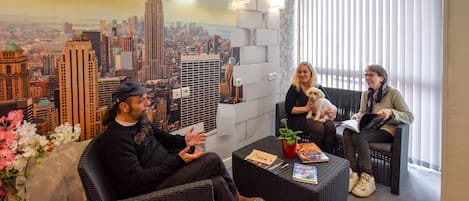 A room with a cityscape mural, wicker furniture, and a window with blinds.