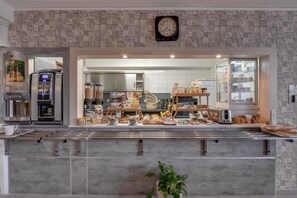 A bakery counter with various baked goods and a coffee machine. - ConfortT Hotel Thouars (Thouars)