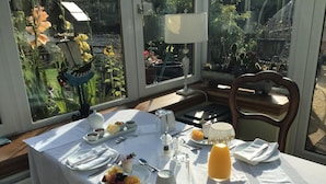 A breakfast table set with plates, bowls, a pitcher, and a glass of orange juice. - The Haven B&B (Castle Douglas)