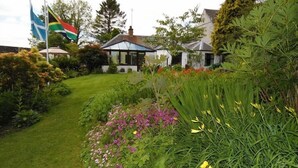 A house with a garden, a flag, and a clear sky. - The Haven B&B (Castle Douglas)