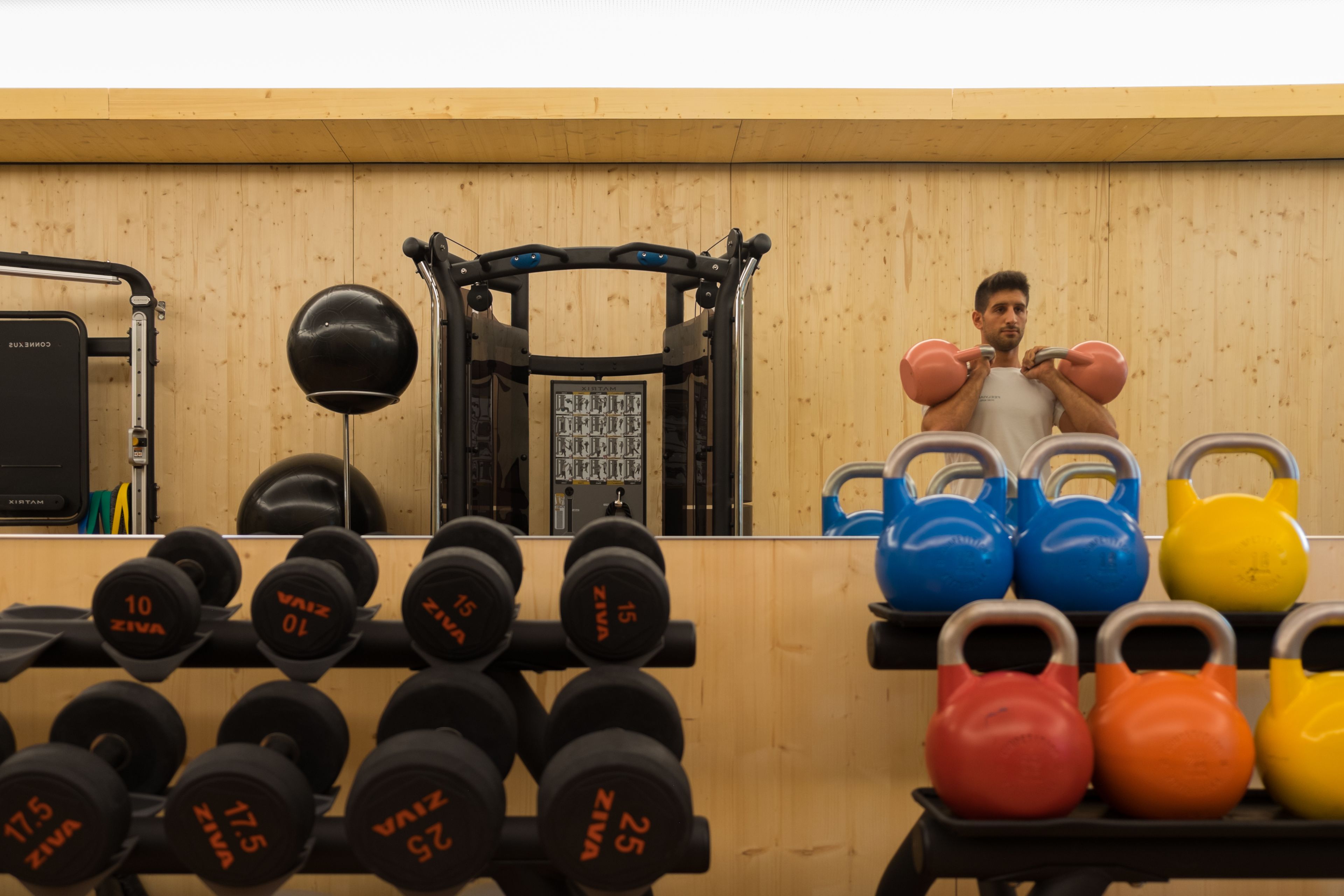 A gym with weightlifting equipment, including dumbbells and kettlebells, and a pull-up bar.