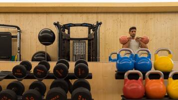 A gym with weightlifting equipment, including dumbbells and kettlebells, and a pull-up bar.