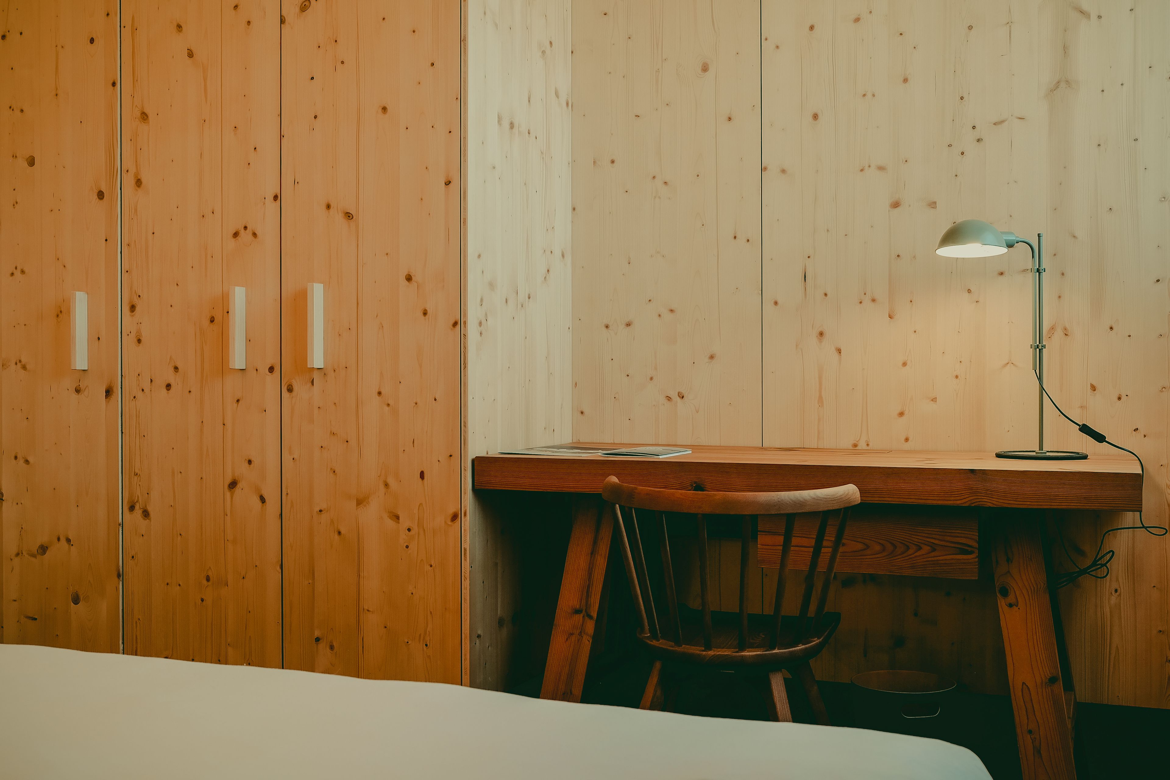 Une pièce en bois avec un bureau, une chaise et un lit.