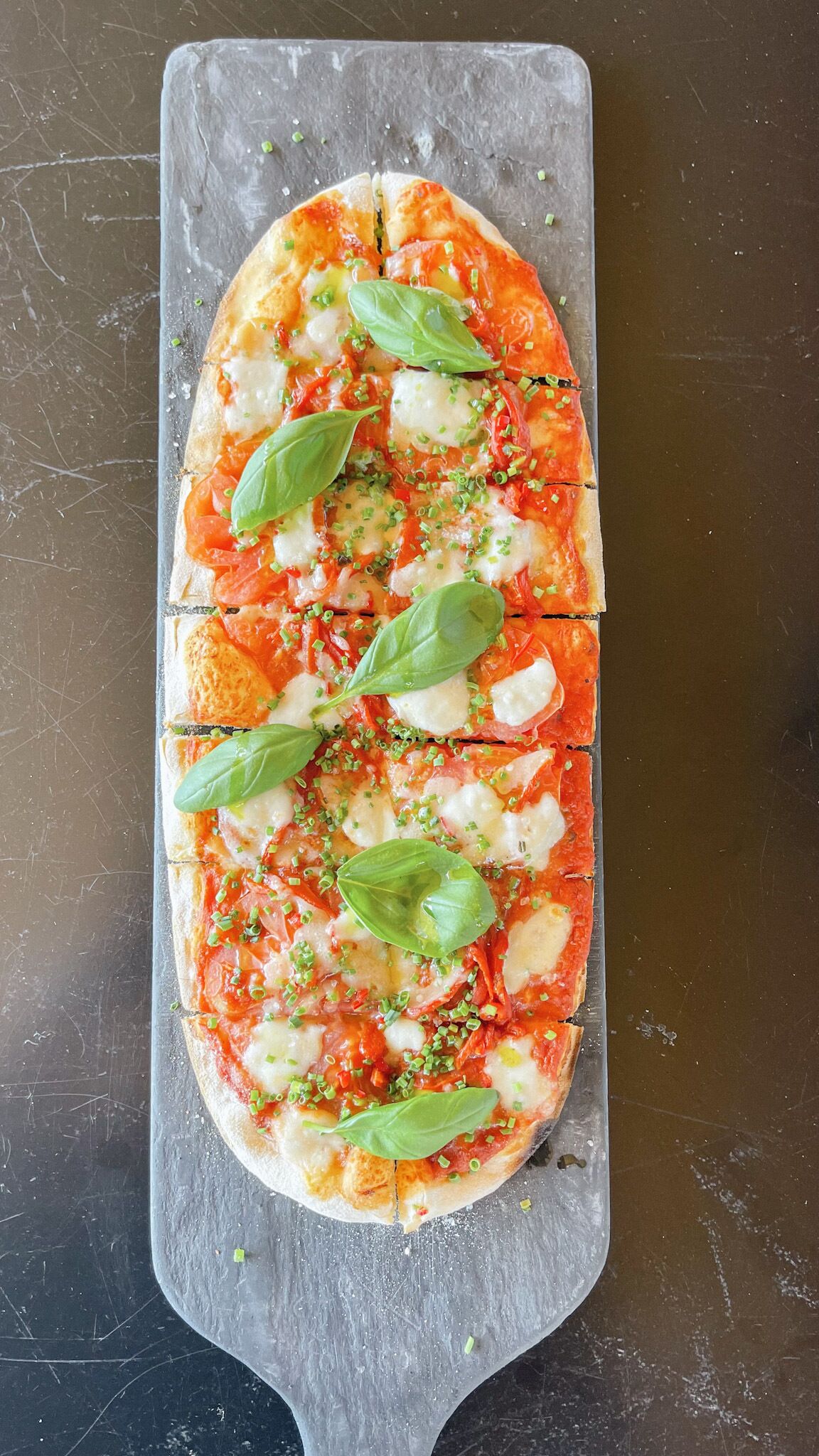 A pizza on a slate board.
