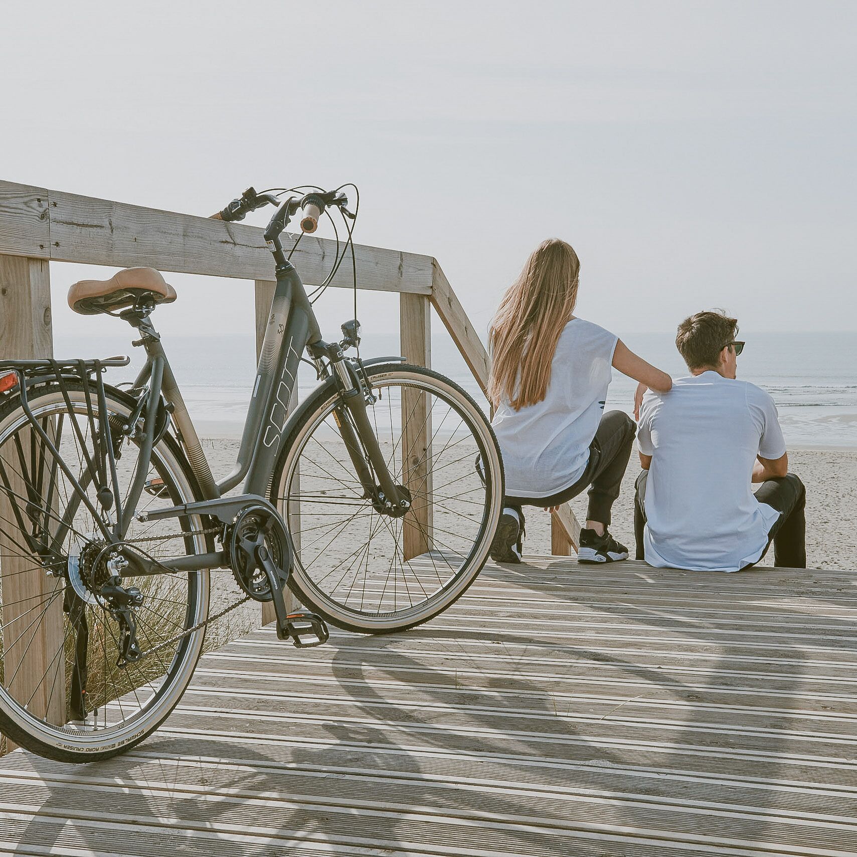 Un muelle de madera con una bicicleta estacionada, con vista a una playa.