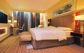 A hotel room with a large bed, a desk with a chair, a TV, and a large window with curtains. - Park Inn by Radisson Kigali (Kigali)